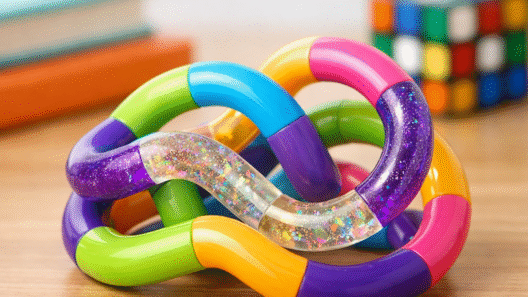 Tangle fidget coloré aux maillons courbés multicolores et pailletés posé sur un bureau — test et avis 2026